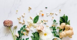 Assortiment d'herbes, de fleurs, d'ail, de gingembre, de shilajit pur, de shilajit en bocal, de shilajit resine avec des pilules et des gélules sur une surface blanche.