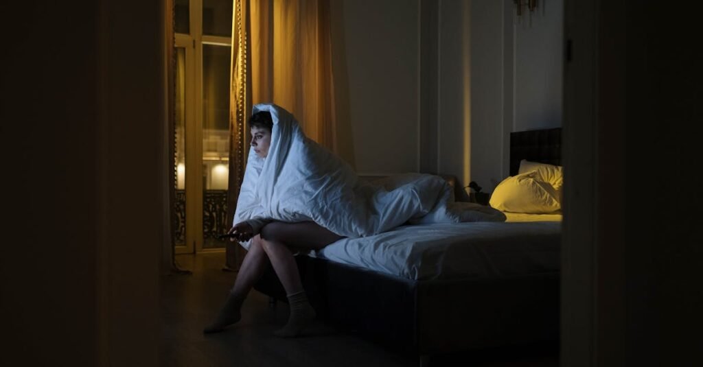 Une personne est assise sur un lit la nuit, avec du shilajit, du shilajit pur, du shilajit en bocal et du shilajit resine à côté d'elle, en utilisant un smartphone.